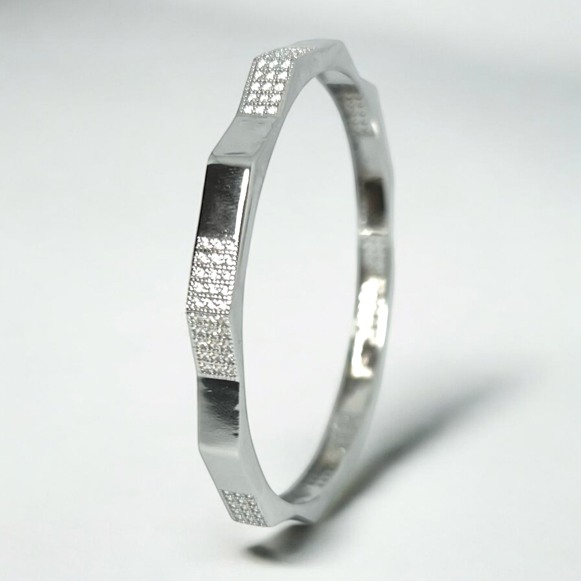 The Zeneer Cuff – Polished Silver Brilliance by Zevaayra is a sterling silver bracelet with a geometric, angular design and four textured sections featuring sparkling cubic zirconia, shown on a plain white background.