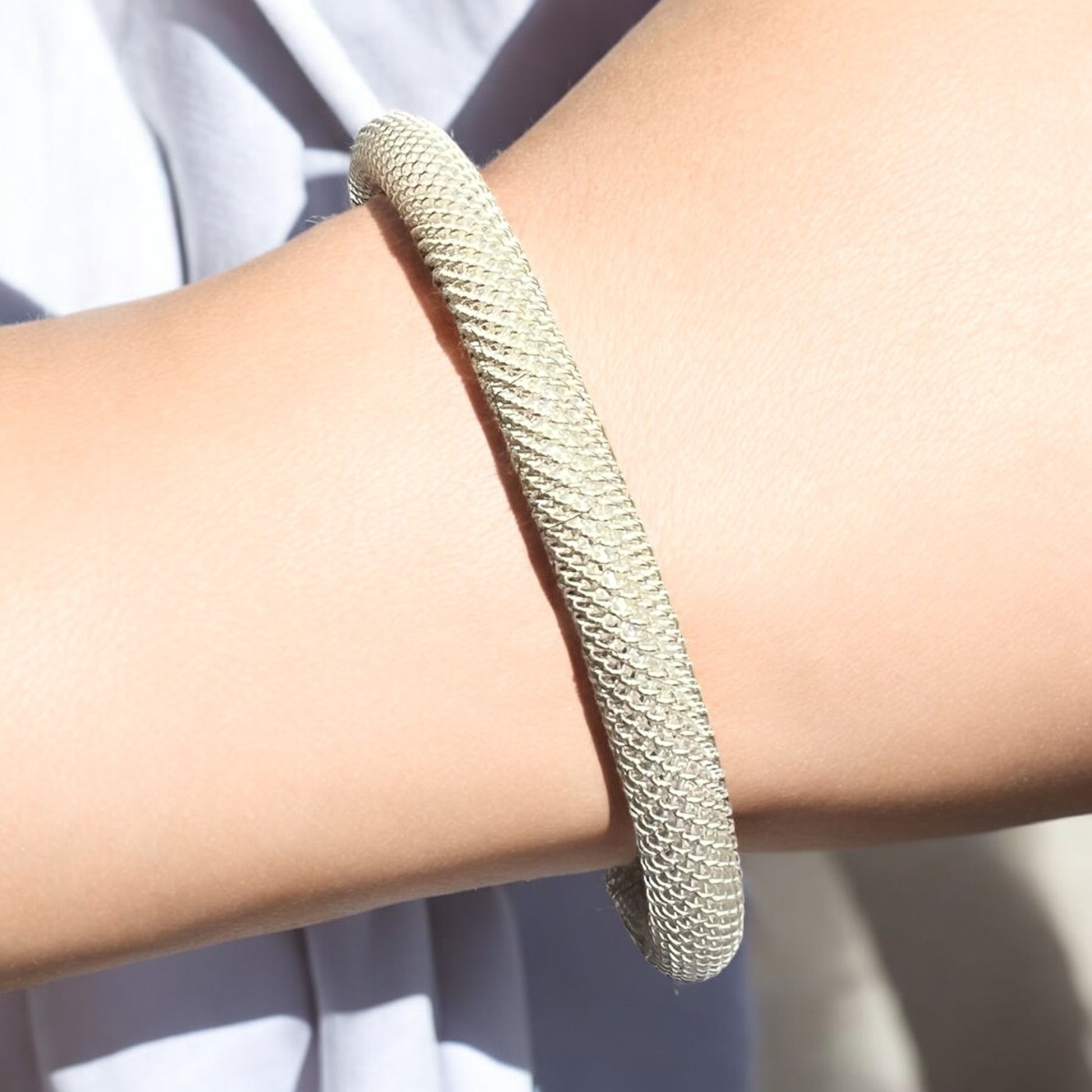 A close-up of a wrist wearing the Zevaayra Luna Mesh Cuff, a minimalist, tarnish-resistant bracelet with a mesh-like texture, shown against a light background.